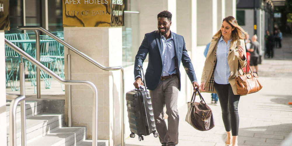 Staff member helping guest into hotel with her bags