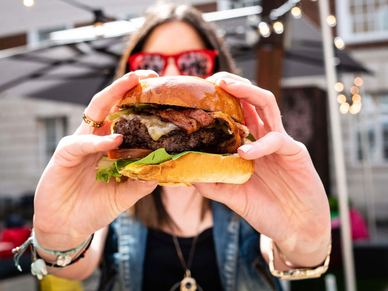Woman wearing sunglasses holding burger