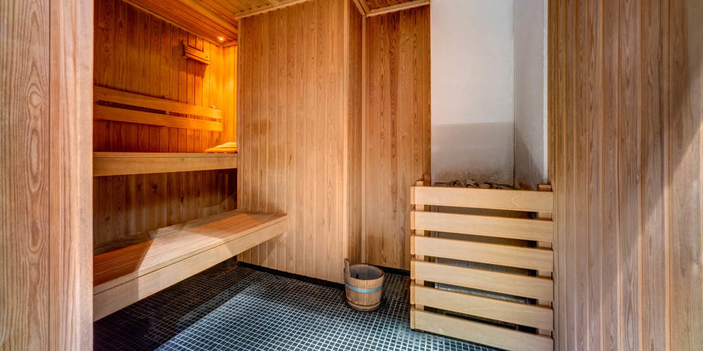Sauna with blue and white floor tiles and wooden wall panels and seating