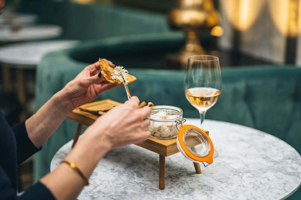 Female using knife to spread food on toast with glass of white wine in Lazy Ballerinas