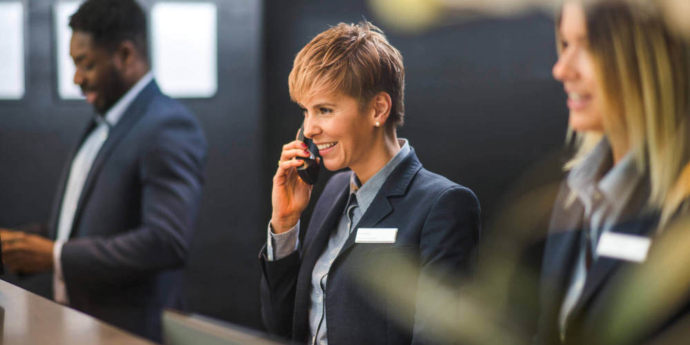 Three receptionists with female employee in the middle on the phone
