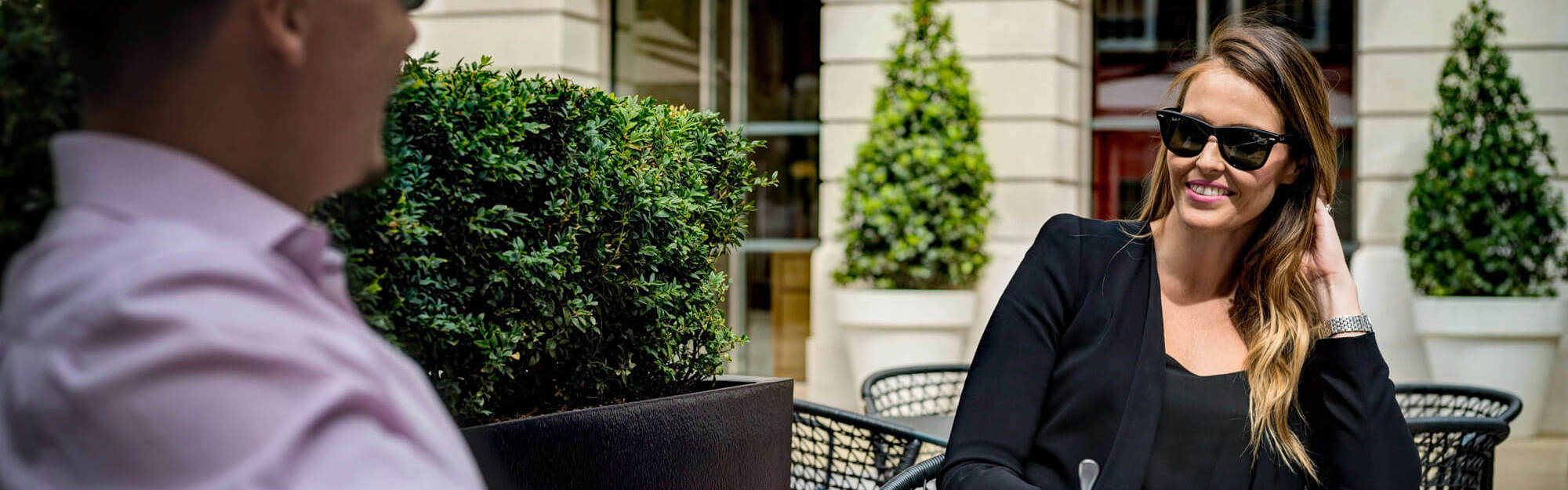 Couple sitting at table outside wearing sunglasses