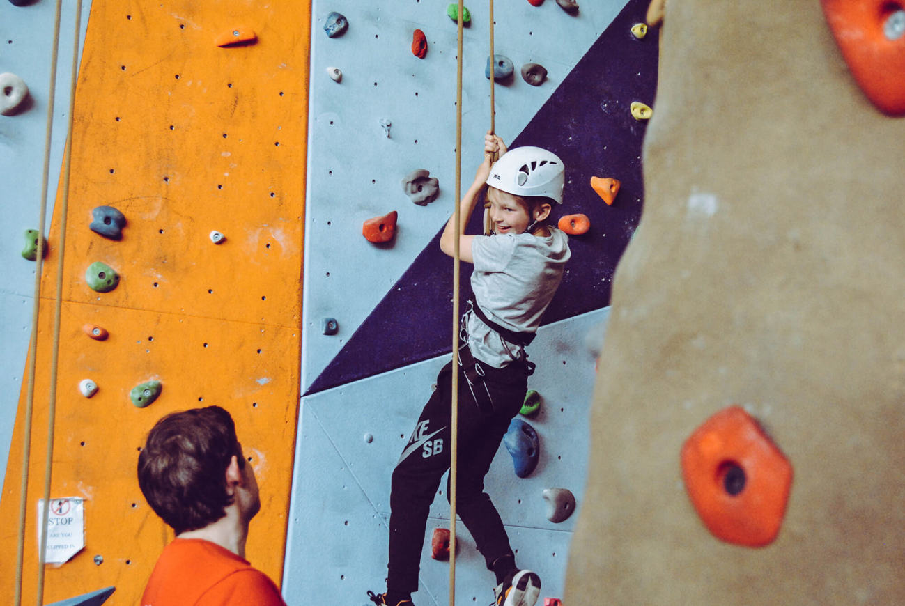 Young boy abseiling down indoor climbing wall