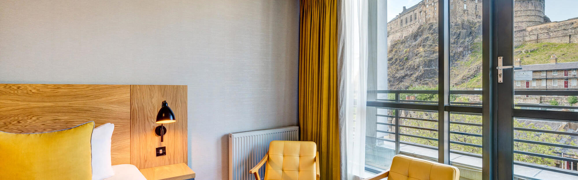 Double bed with views onto Edinburgh Castle in Apex Grassmarket's Deluxe Castle View Room