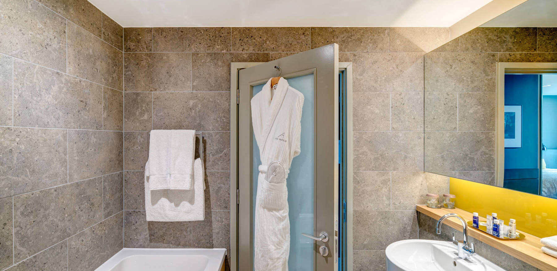 Deluxe Room bathroom with bath and robe hanging on back of door