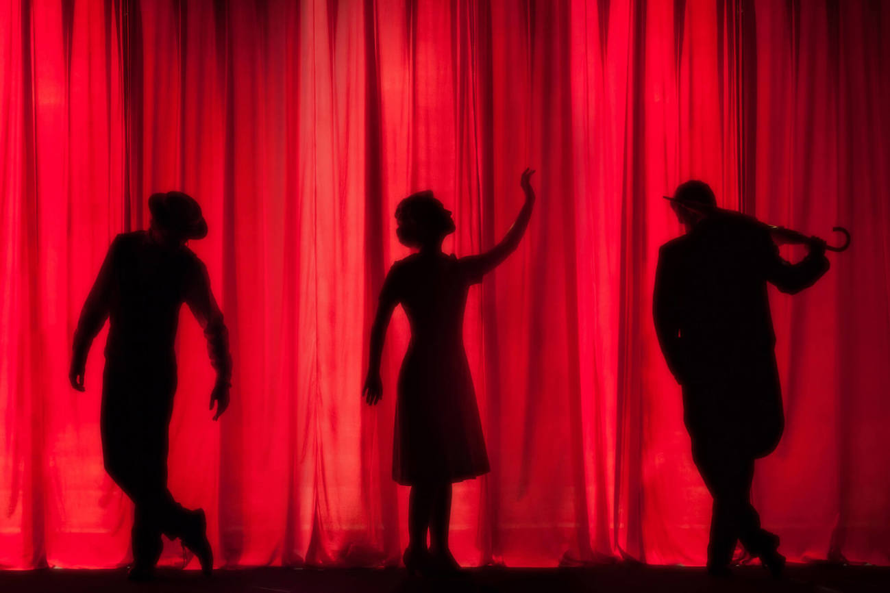 Theatre performer shadows in front of red curtain