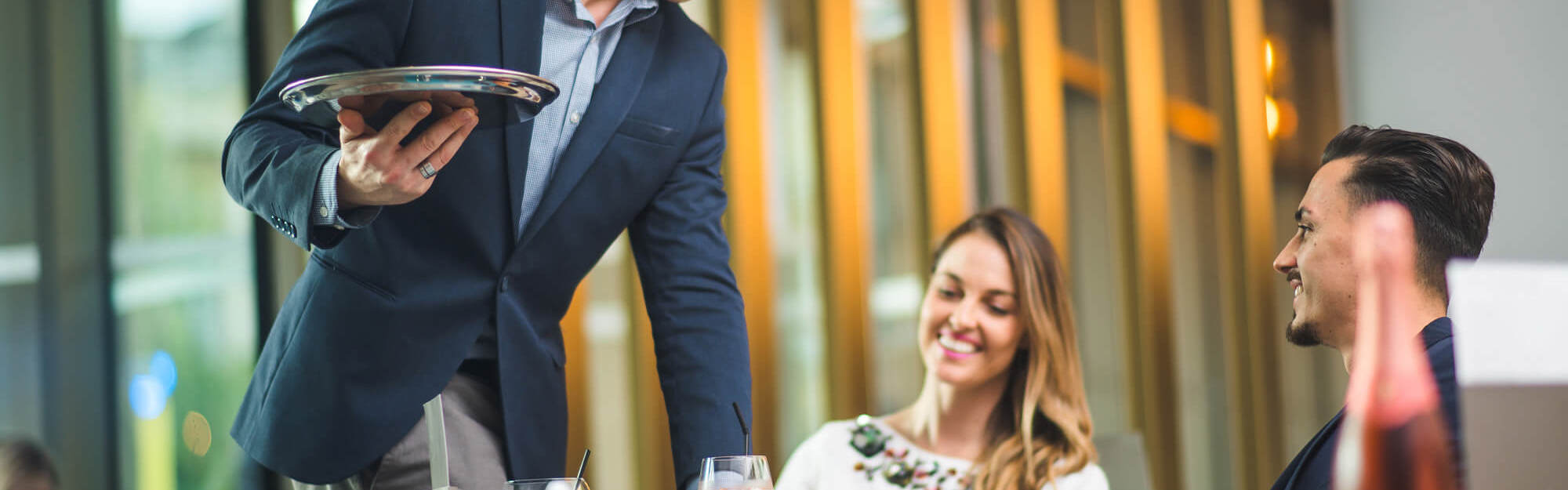 Couple of guests being served drinks by waiter